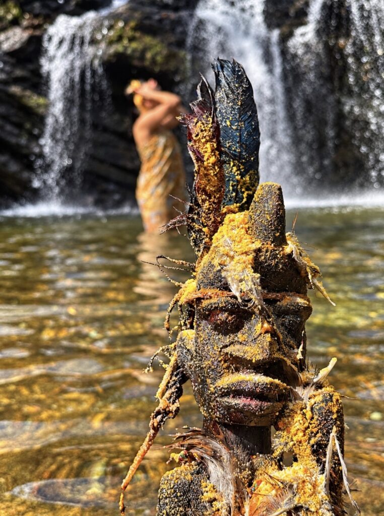 Statue vodun sculptée devant une chute d’eau
